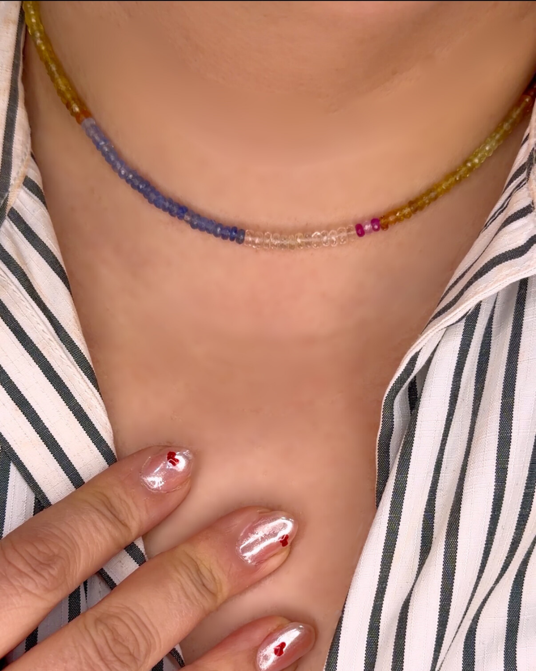 Close-up of a person wearing a colorful beaded necklace with a striped shirt.