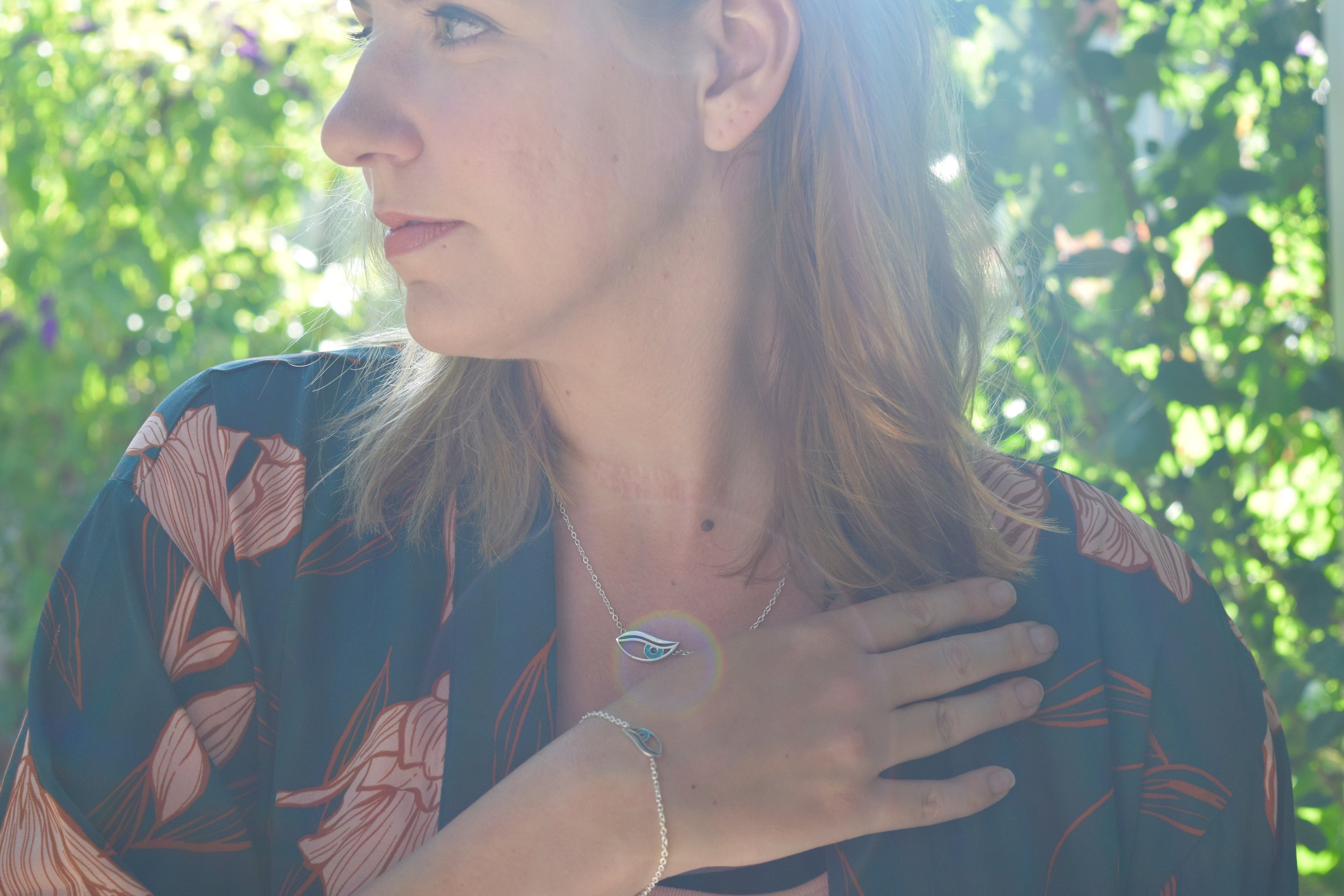 Blonde woman wearing sterling silver evil eye necklace and evil eye bracelet