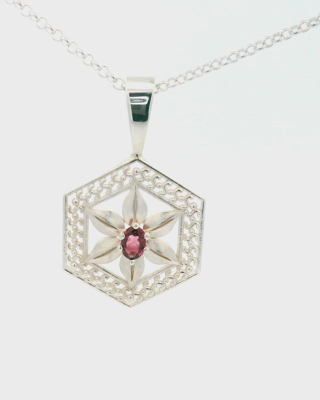 Silver hexagonal pendant with a spinel gemstone on a white background