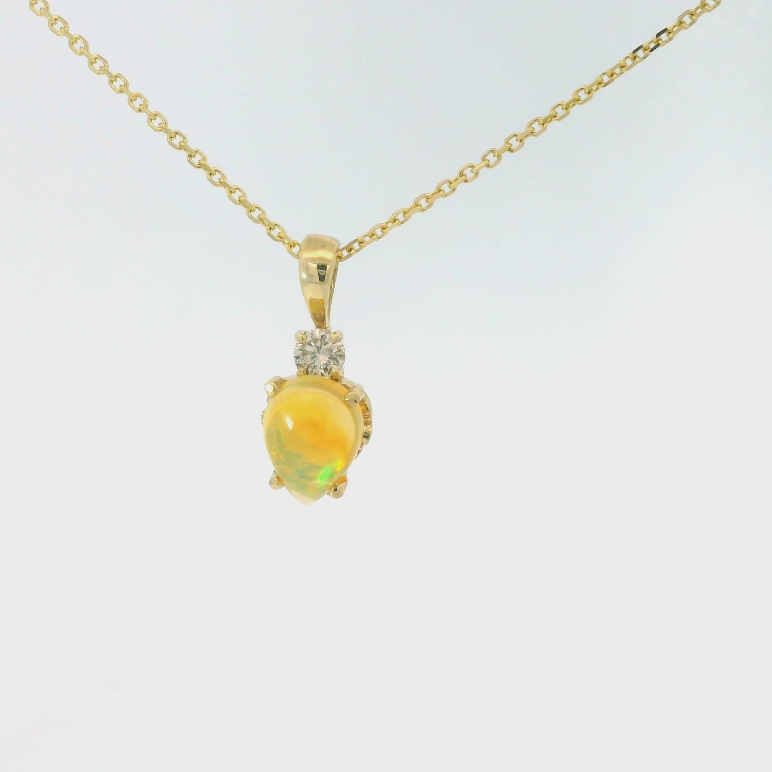 Gold necklace with a opal gemstone pendant and diamond on a white background