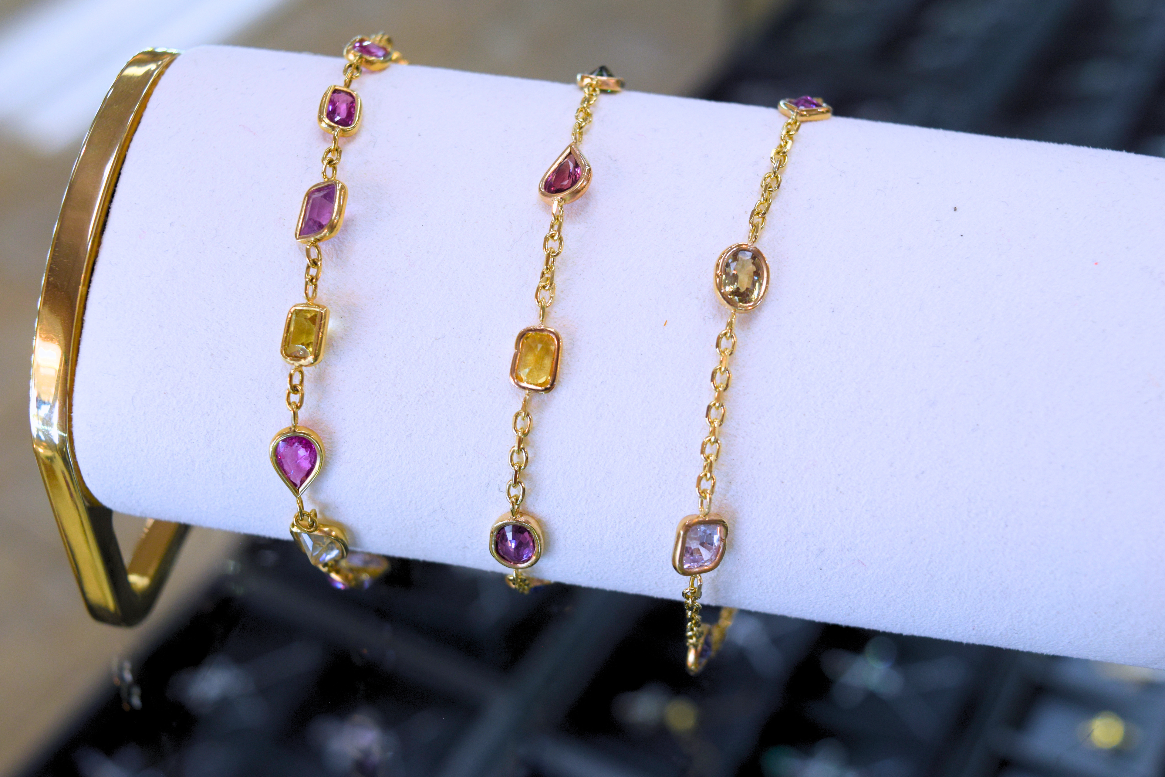 Gold bracelets with sapphire gemstones on a white surface